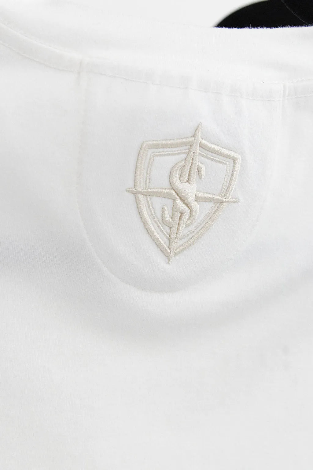 Close-up of the SPHILISTINE Signature T-shirt tonal embroidered emblem on white cotton jersey